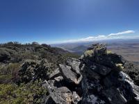 An ancient cairn on top of a mountain with a blue sky in the background